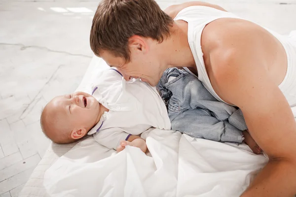 Jeune père avec son fils de neuf mois sur le lit à la maison — Photo