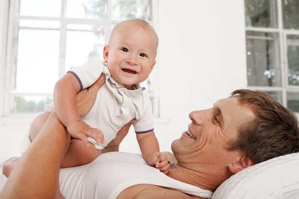 Jovem pai com seu filho de nove meses de idade na cama em casa — Fotografia de Stock