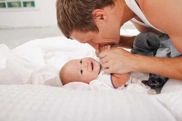 Junger Vater mit seinem neun Monate alten Sohn zu Hause auf dem Bett — Stockfoto