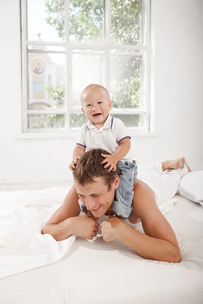 집에서 침대에 그의 9 개월 된 아들과 함께 젊은 아버지 — 스톡 사진