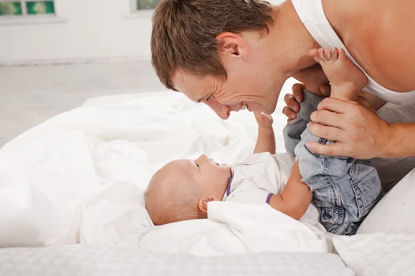 Young father with his nine months old son on the bed at home — Stock Photo, Image