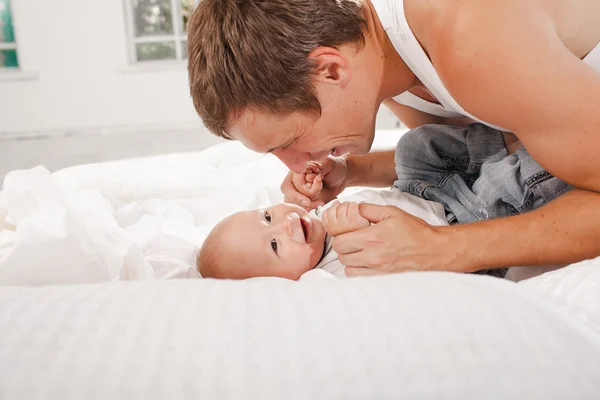 Young father with his nine months old son on the bed at home — Stock Photo, Image