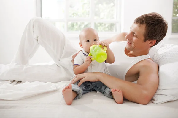 Young father with his nine months old son on the bed at home