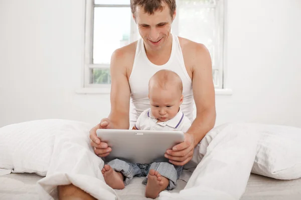 Young father with his nine months old son with digital tablet