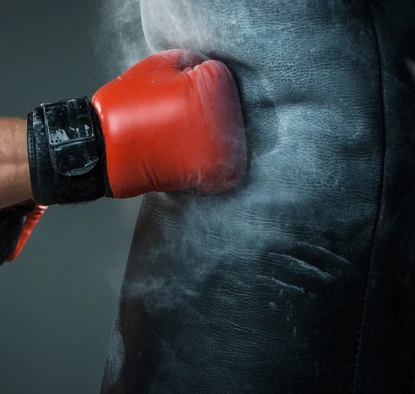 Main de boxeur et sac de boxe sur fond noir — Photo