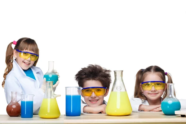 Los tres niños lindos en la lección de química haciendo experimentos sobre fondo blanco — Foto de Stock