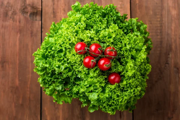 Salade de laitue et tomates cerises sur fond de bois — Photo