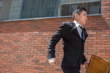 Chinese young businessman running in a city street