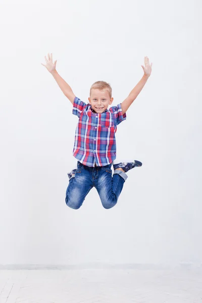 Menino feliz pulando no fundo branco — Fotografia de Stock