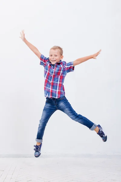 Menino feliz pulando no fundo branco — Fotografia de Stock