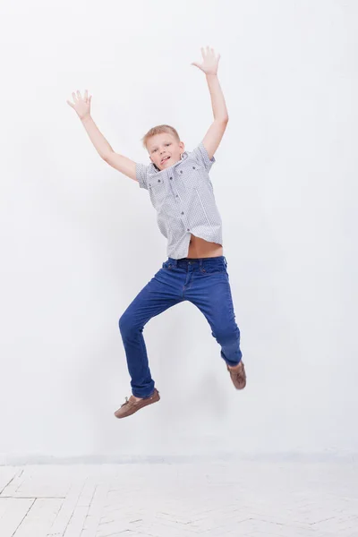 Menino feliz pulando no fundo branco — Fotografia de Stock