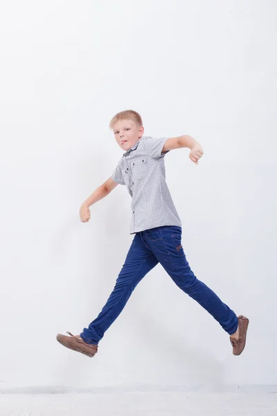 Menino feliz pulando no fundo branco — Fotografia de Stock