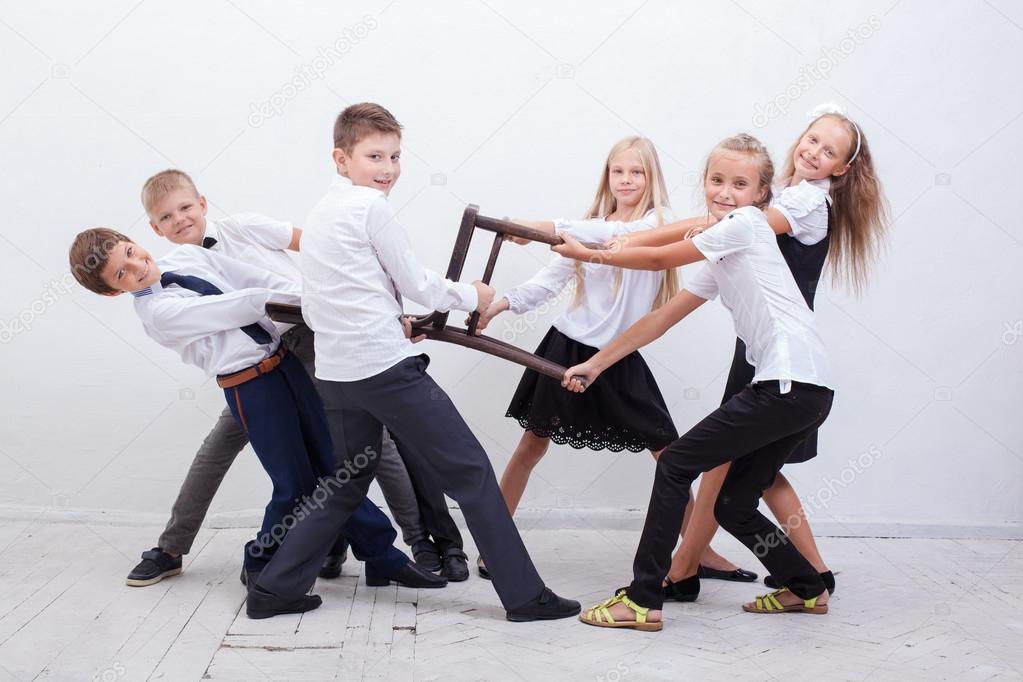 Kids playing tug of chair - girls versus boys,