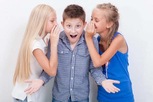 Teenager-Mädchen flüstern in die Ohren eines geheimen Teenager-Jungen auf weißem Hintergrund — Stockfoto