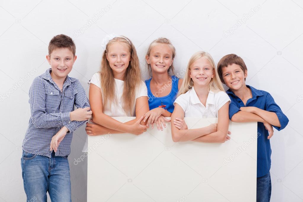 Happy smiling group of kids, boys and girls, showing board 