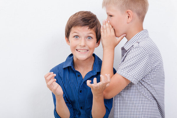 Teenage boy whispering in the ear a secret to friendl on white  background