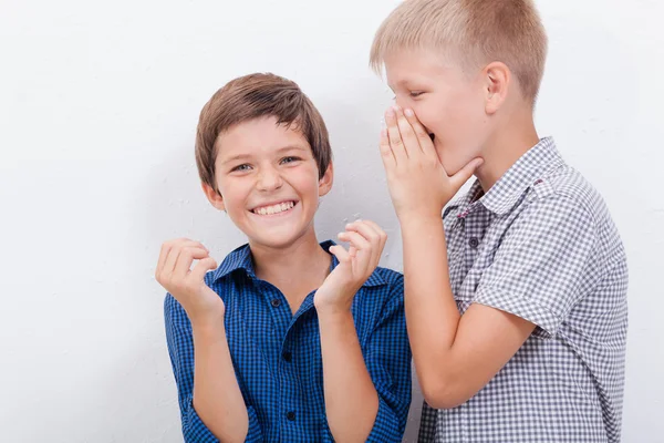 Мальчик-подросток шепчет на ухо секрет дружбы на белом фоне — стоковое фото