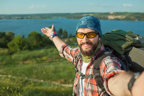 Jeune homme caucasien avec sac à dos debout sur le sommet de la colline — Photo