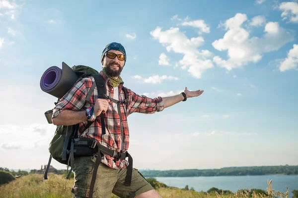 Young caucasian man with backpack standing on the top of hill — Stock Photo, Image