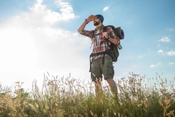 Young caucasian man with backpack standing on the top of hill — Stock Photo, Image