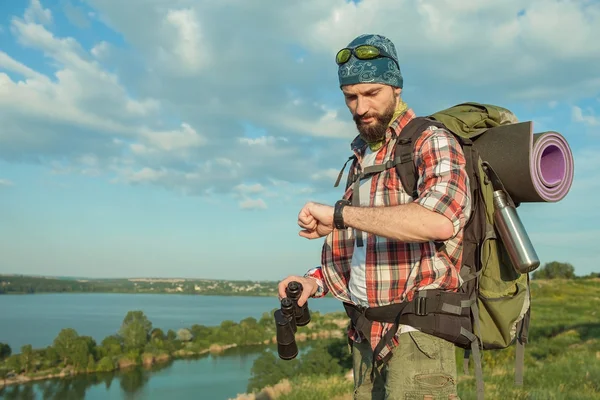 Young caucasian man with backpack standing on the top of hill — Stock Photo, Image