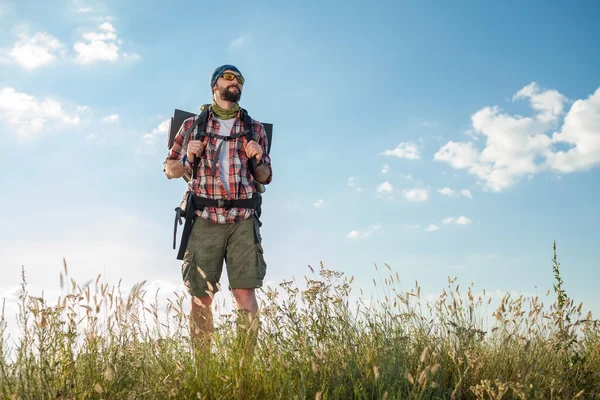 Mladý muž běloch s batoh stojí na vrcholu kopce — Stock fotografie