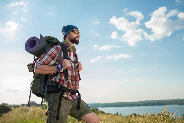 Young caucasian man with backpack standing on the top of hill — Stock Photo, Image