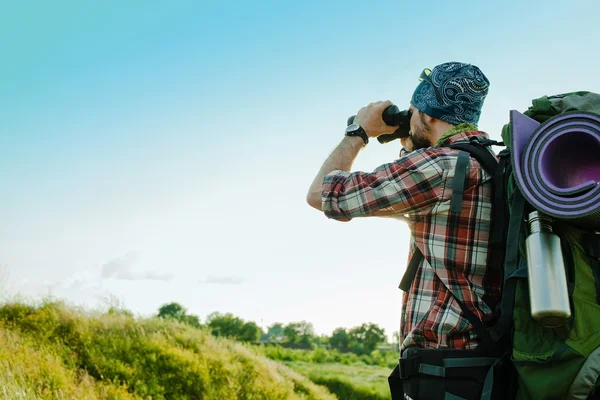 Young caucasian man with backpack standing on the top of hill — Stock Photo, Image