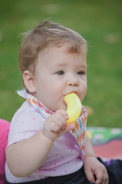 Ребенок, которому меньше года, играет с игрушечным бананом — стоковое фото