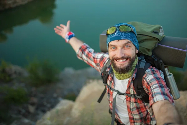 Young caucasian man with backpack standing on the top of hill — Stock Photo, Image