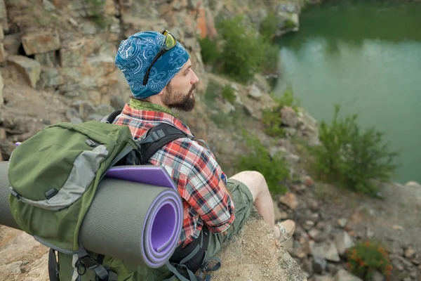 Jeune homme caucasien avec sac à dos assis sur le sommet de la colline — Photo