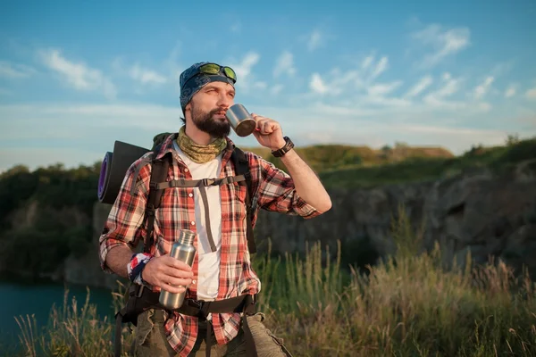 Kaukasische jongeman met rugzak rusten en drinkwater — Stockfoto