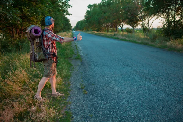 年轻的白种人旅游搭车沿着一条路. — 图库照片