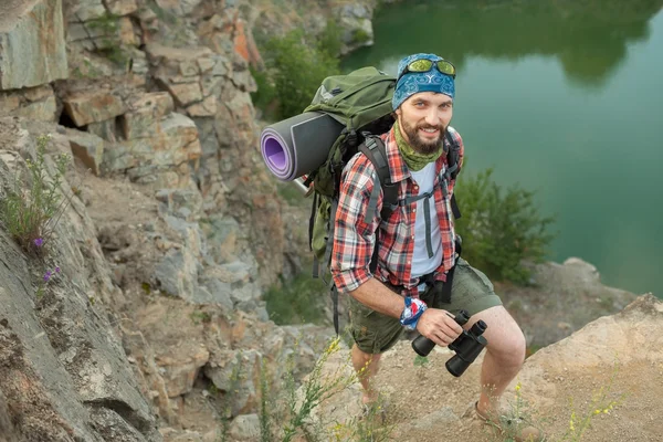 Kaukasische jongeman met rugzak de rots klimmen — Stockfoto