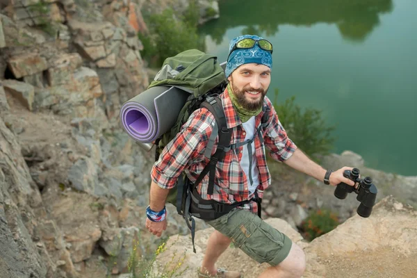 Kaukasische jongeman met rugzak de rots klimmen — Stockfoto