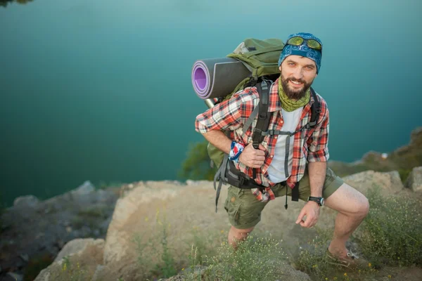 Kaukasische jongeman met rugzak de rots klimmen — Stockfoto