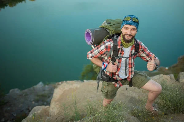 Young caucasian man with backpack climbing the rock — Stock Photo, Image