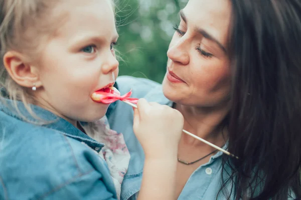 Die junge Mutter und Tochter auf grünem Gras Hintergrund — Stockfoto