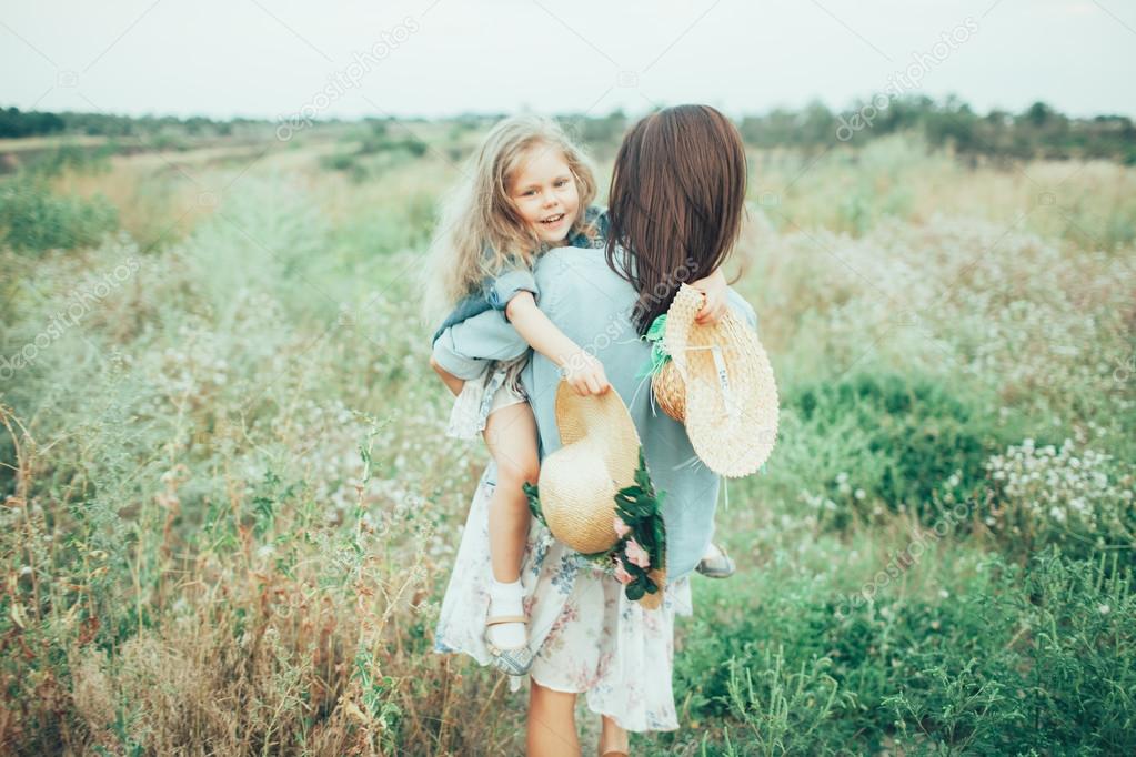 The young mother and daughter on green grass background