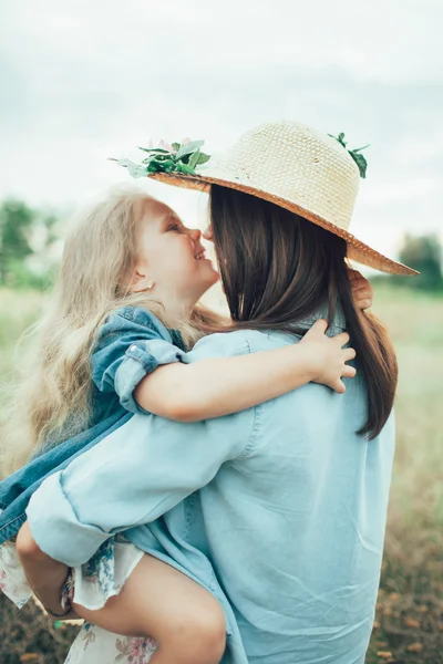 Die junge Mutter und Tochter auf grünem Gras Hintergrund — Stockfoto