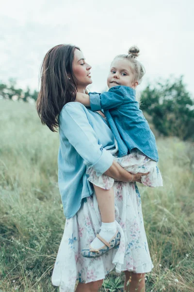 A jovem mãe e filha no fundo de grama verde — Fotografia de Stock