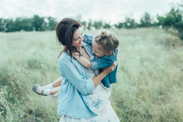 A jovem mãe e filha no fundo de grama verde — Fotografia de Stock
