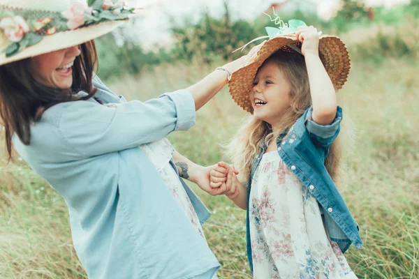 Die junge Mutter und Tochter auf grünem Gras Hintergrund — Stockfoto