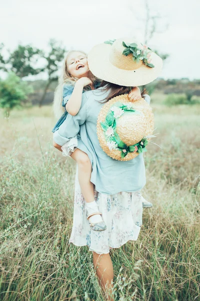 A jovem mãe e filha no fundo de grama verde — Fotografia de Stock