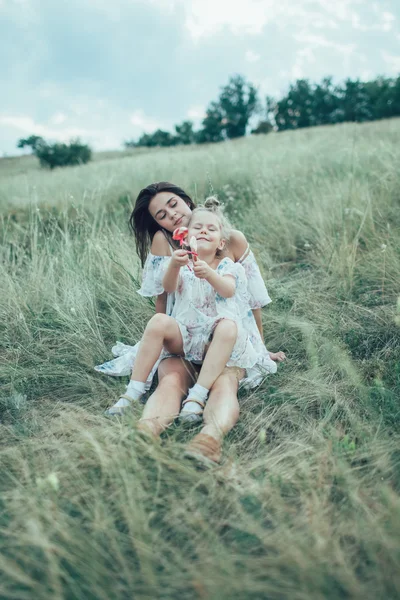 Молодая мать и дочь на зеленом фоне травы — стоковое фото