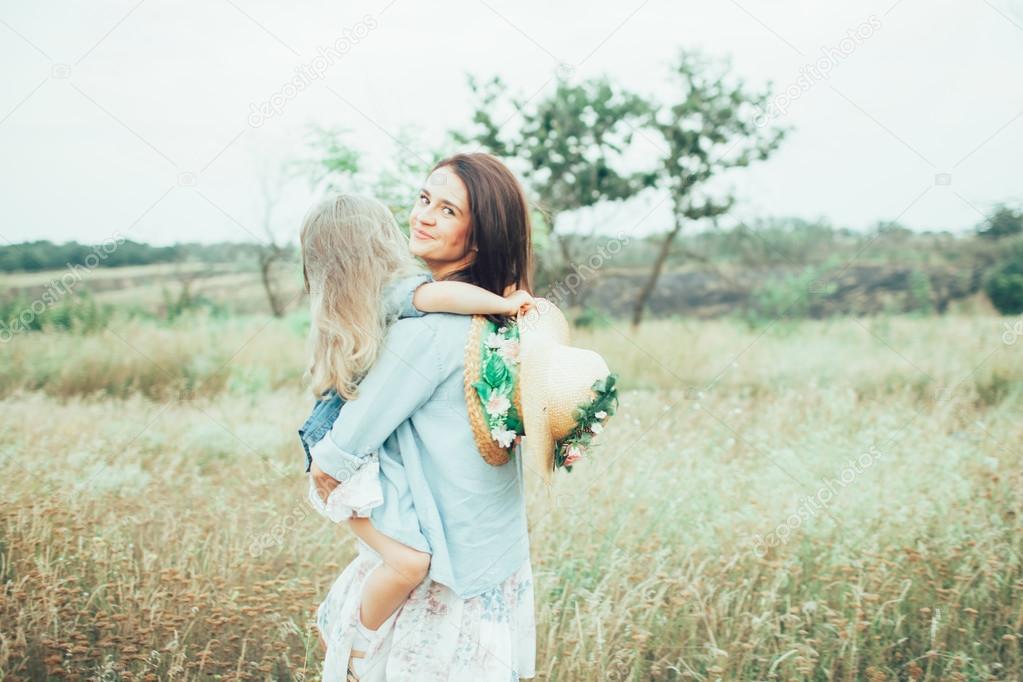 The young mother and daughter on green grass background