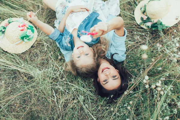 Młoda matka i córka na tle zielonej trawie — Zdjęcie stockowe