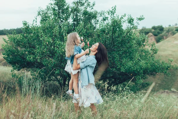 La joven madre y su hija en el fondo de hierba verde —  Fotos de Stock