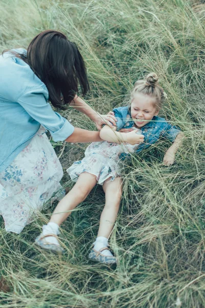 A jovem mãe e filha no fundo de grama verde — Fotografia de Stock