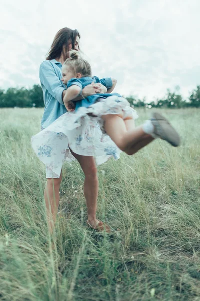 The young mother and daughter on green grass background — Stock Photo, Image